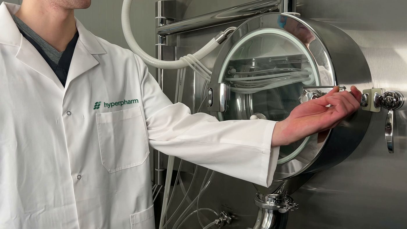 Tablet coating drum at the plant, an operator in a HYPERPHARM coat opening the door